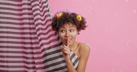 Beautiful dark skinned woman makes hush gesture spreads rumors poses in bathroom Stock Footage 147991353