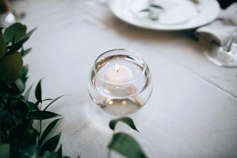 Beautiful decor on the table for the festive dinner: white tablecloth, candle Stock Photos