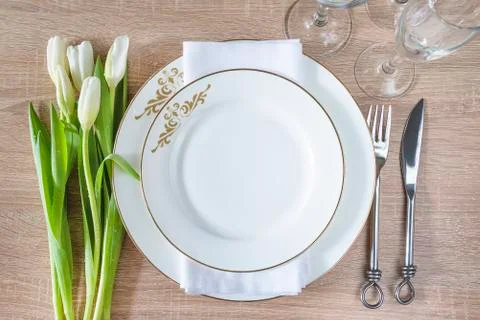 Beautiful decorated table setting. White plates, forged fork and knife, set o Stock Photos