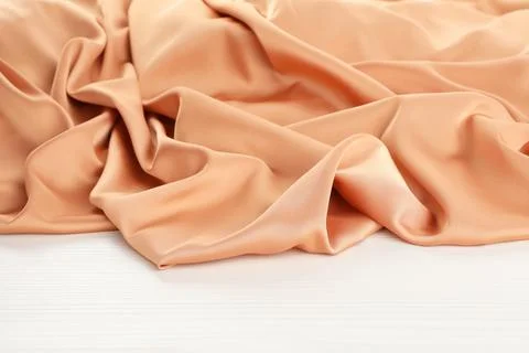 Beautiful delicate peach silk on white wooden table Stock Photos