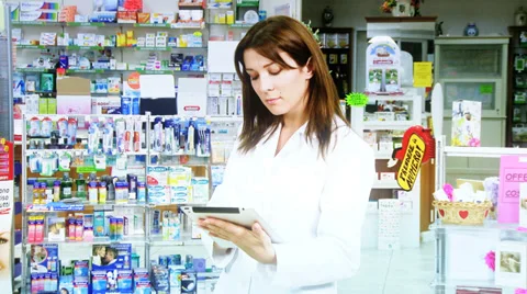 Beautiful doctor in pharmacy working with ipad and smiling happy Stock Footage