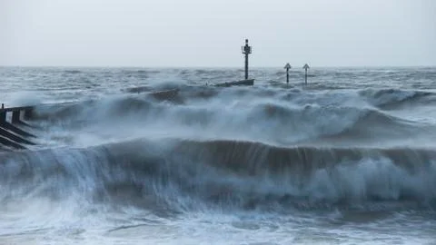 Beautiful dramatic stormy landscape image of waves crashing onto beach at sun Stock Photos