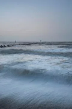 Beautiful dramatic stormy landscape image of waves crashing onto beach at sun Stock Photos