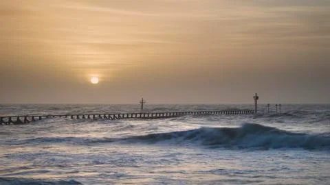 Beautiful dramatic stormy landscape image of waves crashing onto beach at sun Stock Photos