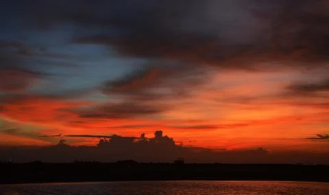 Beautiful dramatic sunset with  orange sky and awesome golden reflection. Stock Photos