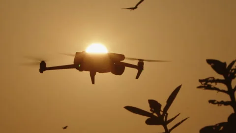 A Beautiful Drone Silhouette Creatively Captured Against a Breathtaking Sunset Stock Footage 303889477