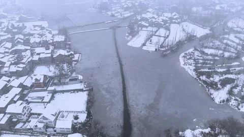 Beautiful Drone view of winter serenity — snow-covered houses under morning mist Stock Footage 310224134