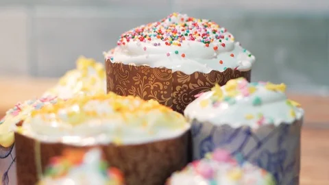 Beautiful Easter cakes decorated with white glaze and colorful sweets. Hand shot Stock Footage 128758960
