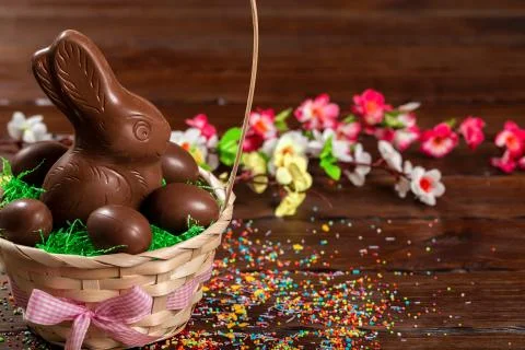 Beautiful Easter composition with chocolate bunny and eggs in a wicker basket Stock Photos