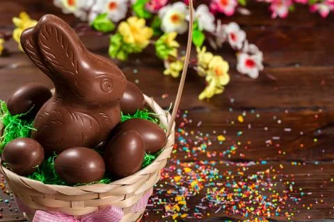 Beautiful Easter composition with chocolate bunny and eggs in a wicker basket Stock Photos