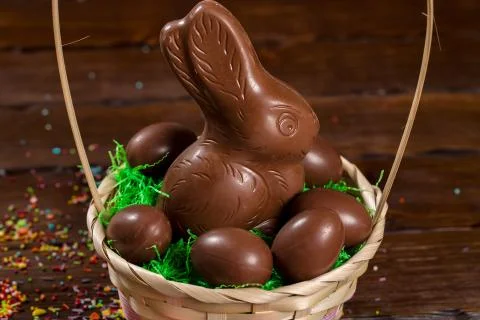 Beautiful Easter composition with chocolate bunny and eggs in a wicker basket Stock Photos