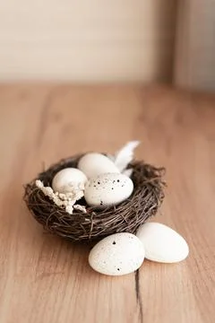 A beautiful Easter nest with three white eggs rests on a wooden surface, de.. Stock Photos