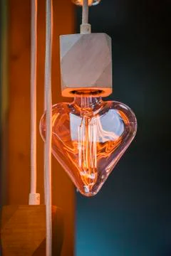 A beautiful Edison light bulb in the shape of a heart. Festive cute heart sha Stock Photos