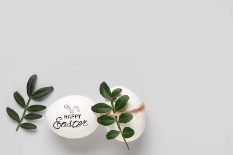 Beautiful eggs with text HAPPY EASTER and green twigs isolated on white backg Stock Photos
