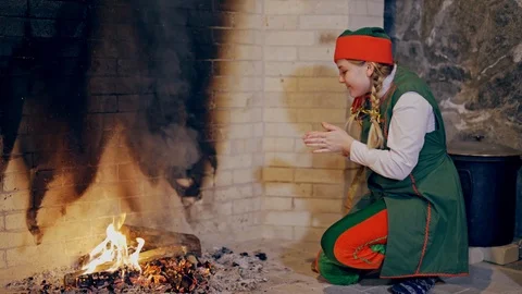 Beautiful elf is getting warm while sitting near the fire at fireplace Stock Footage 111421931