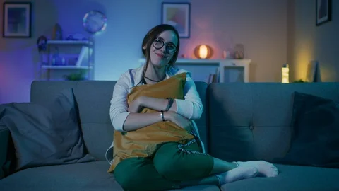 Beautiful Emotional Young Girl in Glasses Sitting on a Couch and Watching TV Stock Footage