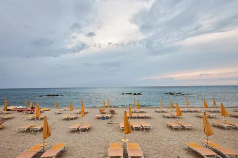 A beautiful empty beach with sun beds and umbrellas of bright orange color. Stock Photos