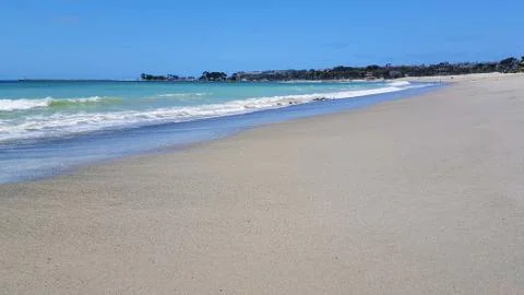 Beautiful empty sandy beach with vibrant blue ocean waves. Stock Photos