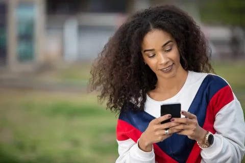 Beautiful ethnic model using phone outside Stock Photos
