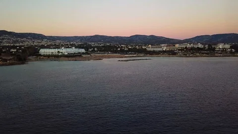 Beautiful evening coast overlooking the tranquil city and mountains. Flying over Stock Footage 107064667