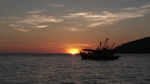 Beautiful evening sunset dramatic color with a silhouette fishing boat Stock Footage