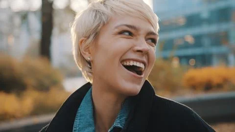 Beautiful excited young caucasian blond woman laughing in the city park Stock Photos