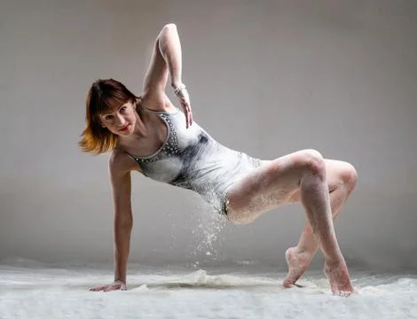 Beautiful expressive ballet dancer posing with flour at studio Stock-Fotos