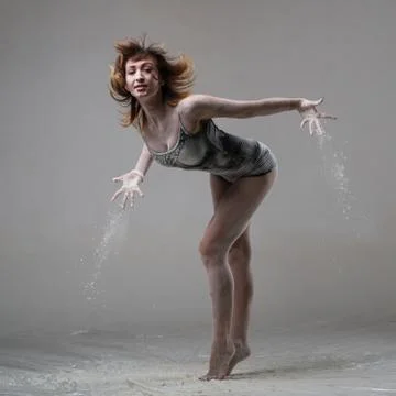 Beautiful expressive ballet dancer posing with flour at studio Stock Photos