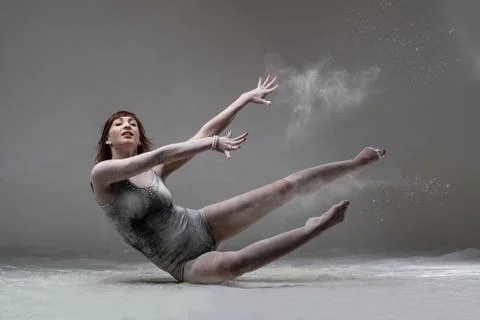 Beautiful expressive ballet dancer posing with flour at studio Stock Photos
