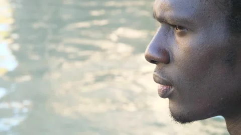 Beautiful face of a young migrant thinking with closed eyes on the river bank Stock Footage 240392689