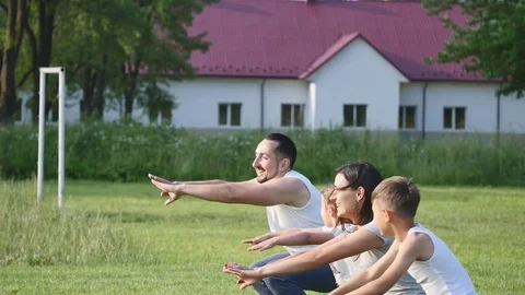 Beautiful family doing physical jerks outdoor. Family tilts and do sport Stock Footage