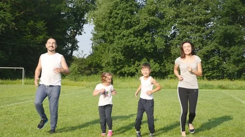Beautiful family doing physical jerks outdoor. Family tilts and do sport Stock Footage