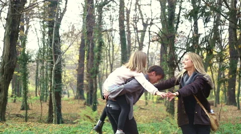 Beautiful family having fun spinning around in the park Stock Footage 59553936