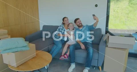 Beautiful family making memorable selfies on smartphone while relaxing, sitting Stock Photos