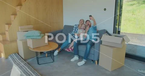 Beautiful family making memorable selfies on smartphone while relaxing, sitting Stock Photos