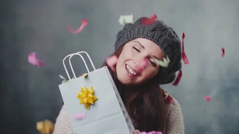 Beautiful fashion model holding gift box under confetti falling, slow motion Stock Footage