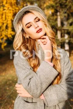 Beautiful fashion model posing in the autumn park. Autumn seasonal fashion. Stock Photos