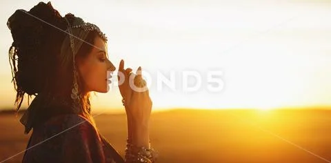 Beautiful fashion model posing in boho style clothes in the rays of the sunse Stock Photos