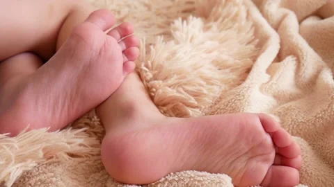 Beautiful feet of a little boy lying on a soft plaid and fidgeting close-up Stock Footage 153330153