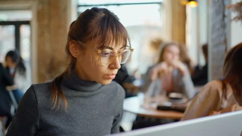 Beautiful female developer or student working, studying by laptop in cafe Stock Footage 128865372