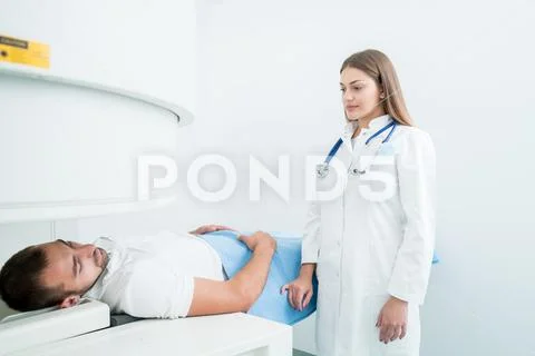 Beautiful female doctor visiting male patient who is in bed. Stock Photos