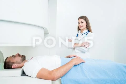 Beautiful female doctor visiting male patient who is in bed. Stock Photos