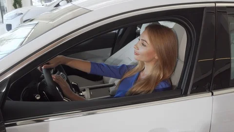 Beautiful female driver smiling to the camera sitting in a new car at the Stock Footage 115584450
