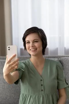 Beautiful female expecting baby sit on couch take cute selfie Stock Photos