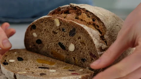 Beautiful female hands cut rustic rye bread with a knife on a wooden board Stock Footage 147031030