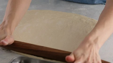 Beautiful female hands in a professional kitchen roll out dough for making bread Stock Footage 148560566