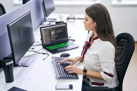 Beautiful female junior software developer working on computer in IT office Stock Photos