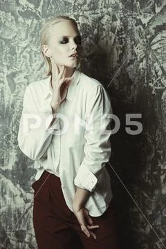 Beautiful female model with dark make-up posing at studio in white shirt and Stock Photos