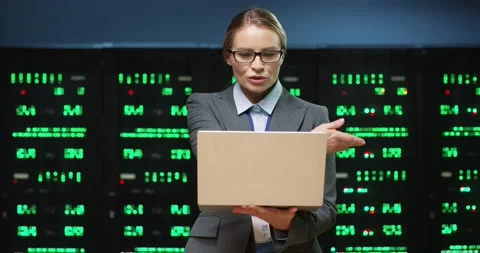 Beautiful female programmer standing in server room holding laptop discussing Stock Footage 152056274