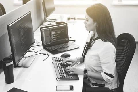 Beautiful female software developer working on computer in IT office, sitting at Stock Photos